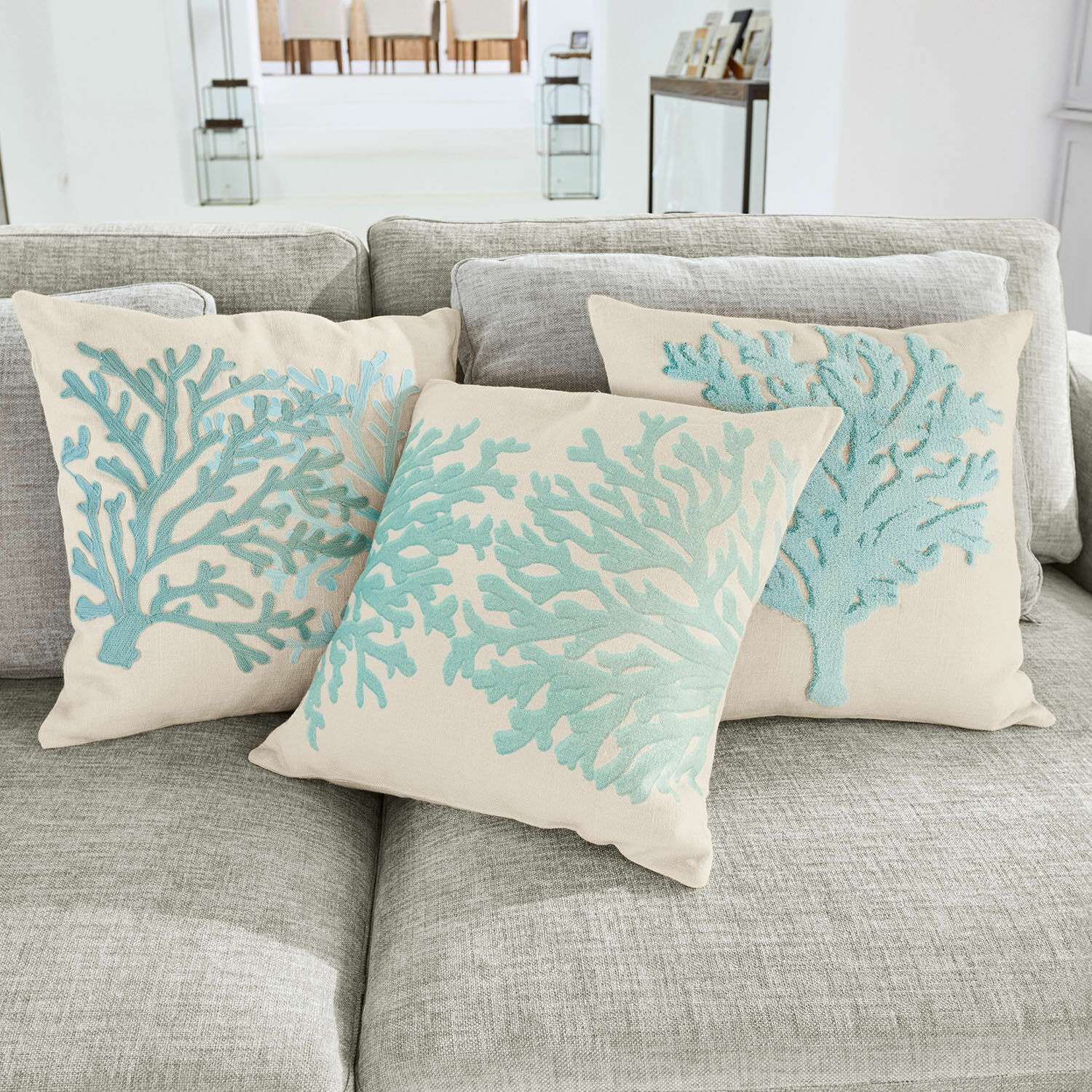 Set di 3 copricuscini Vaiea Cuscini decorativi beige con ricamo corallo azzurro su divano grigio per soggiorno