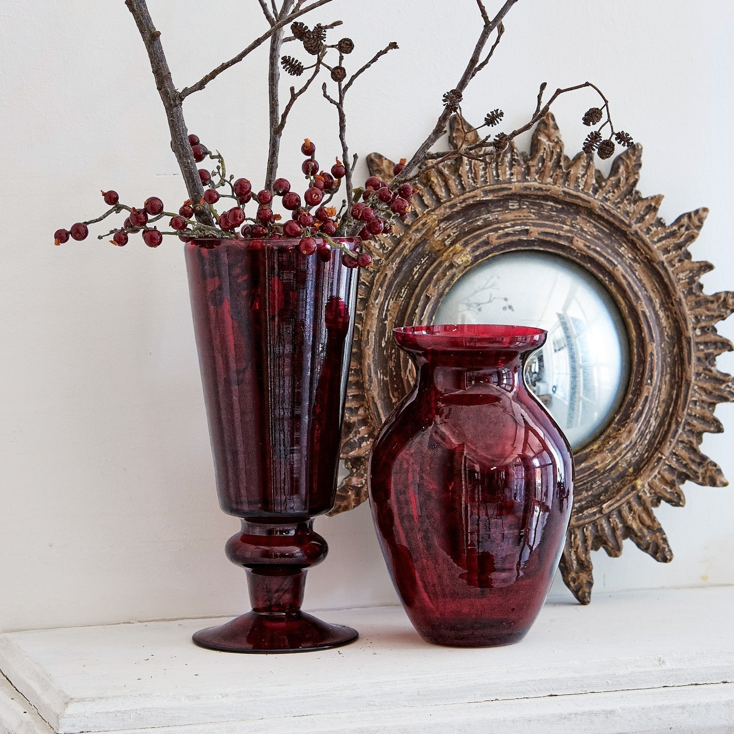 Coppia di vasi Darian Due vasi in vetro rosso su superficie bianca con specchio decorativo sullo sfondo