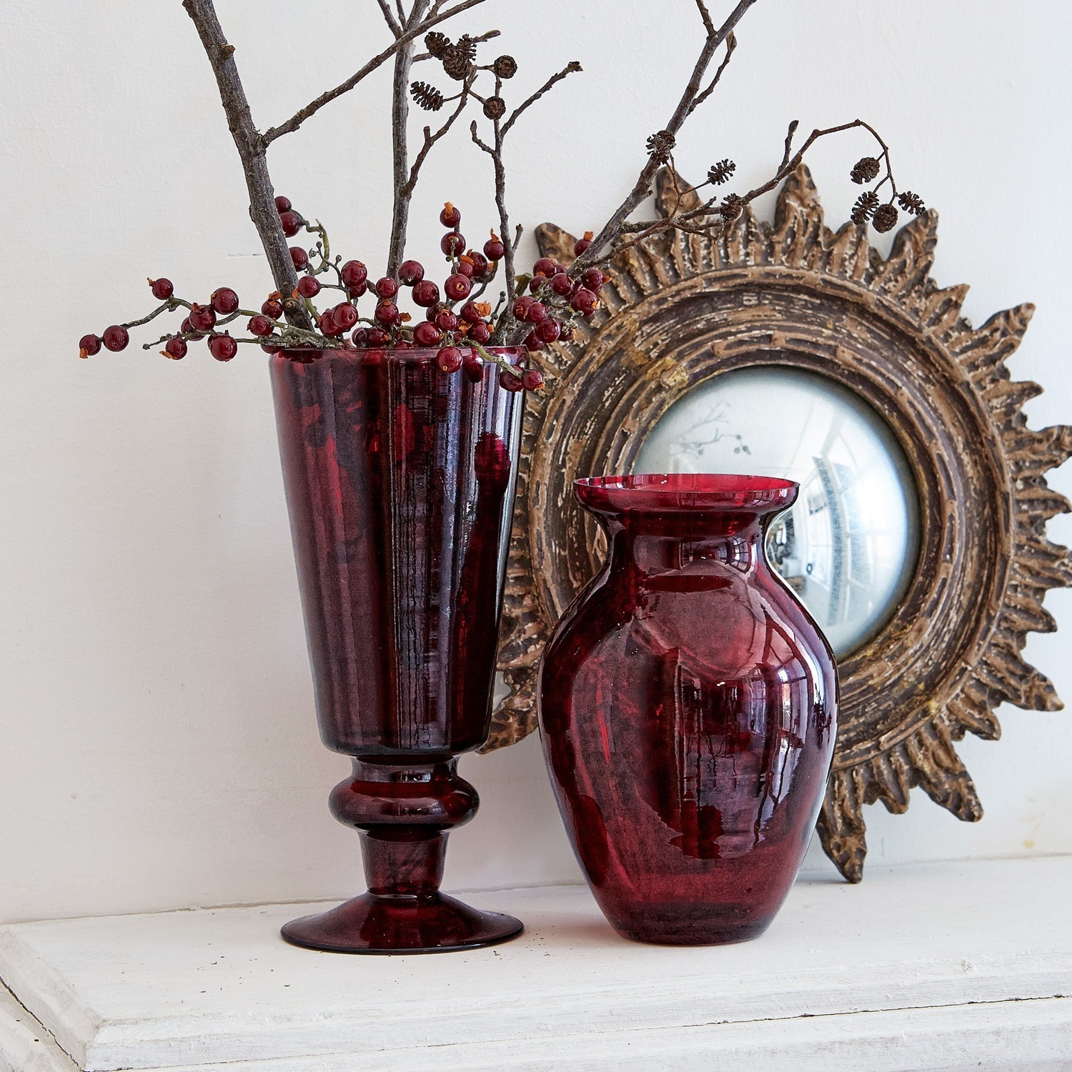 Coppia di vasi Darian Due vasi in vetro rosso su superficie bianca con specchio decorativo sullo sfondo