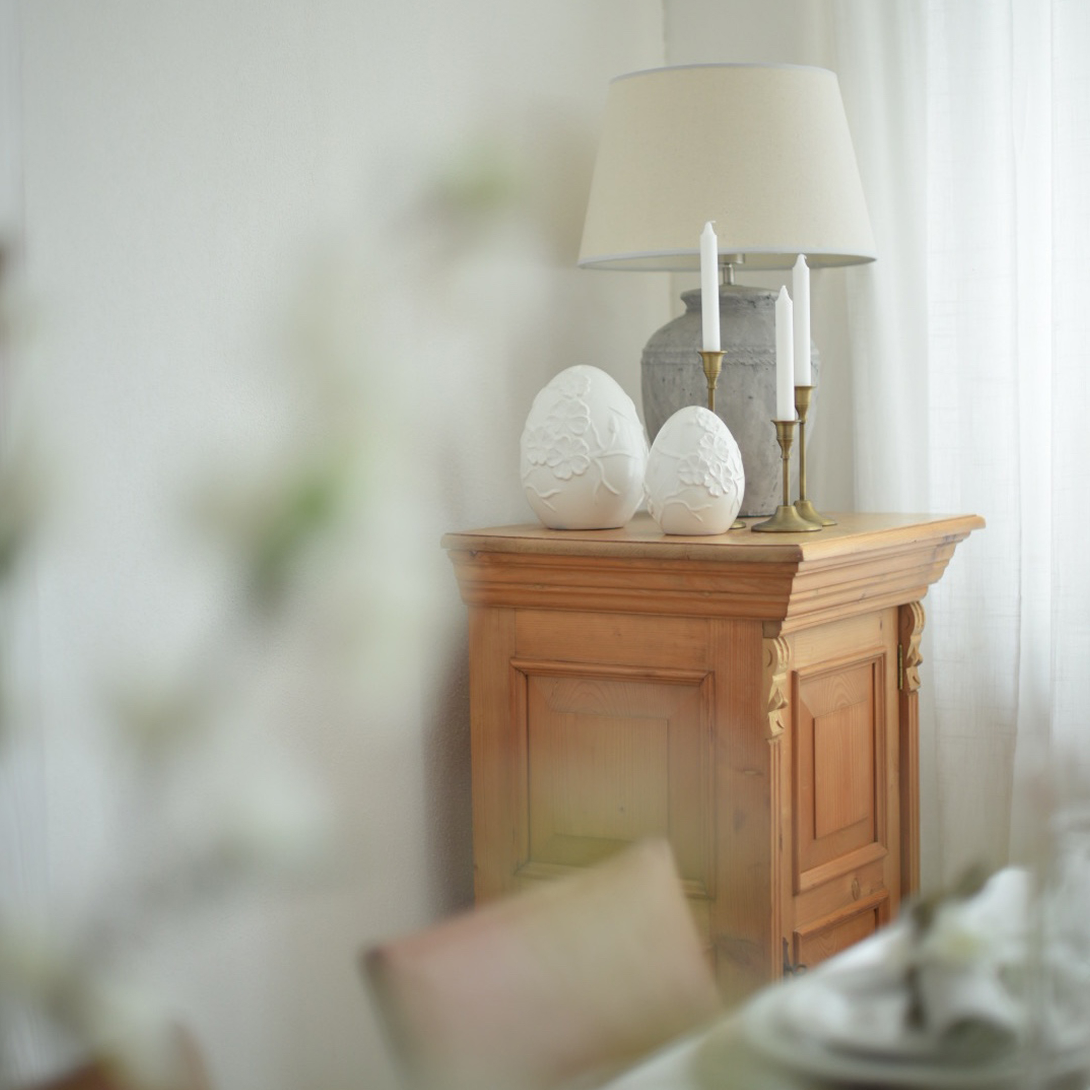 Mobile in legno con lampada, candele e decorazioni in ceramica bianca a forma di uova in interno luminoso