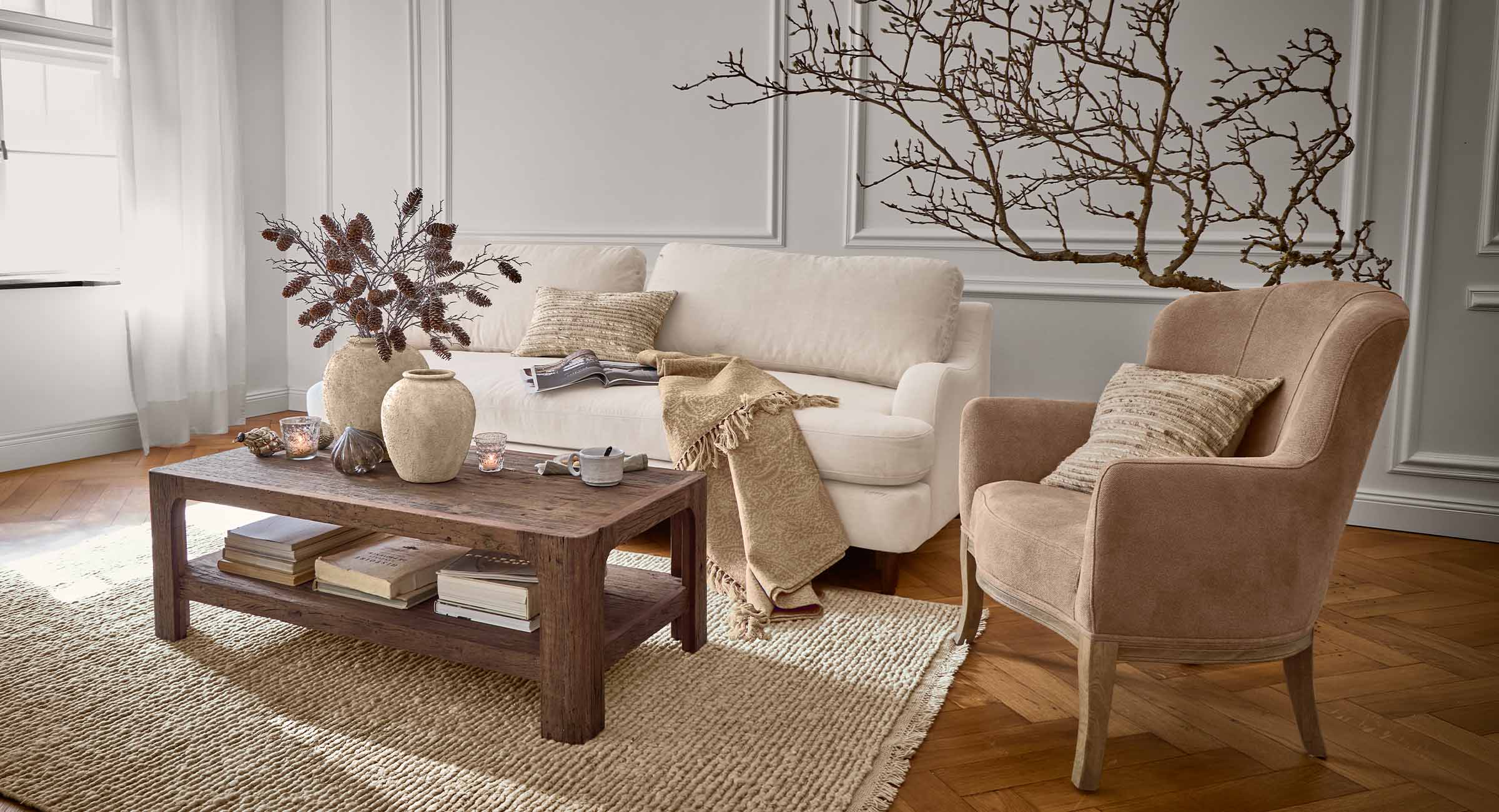 Soggiorno accogliente con divano beige, poltrona marrone e tavolino in legno su tappeto in fibre naturali