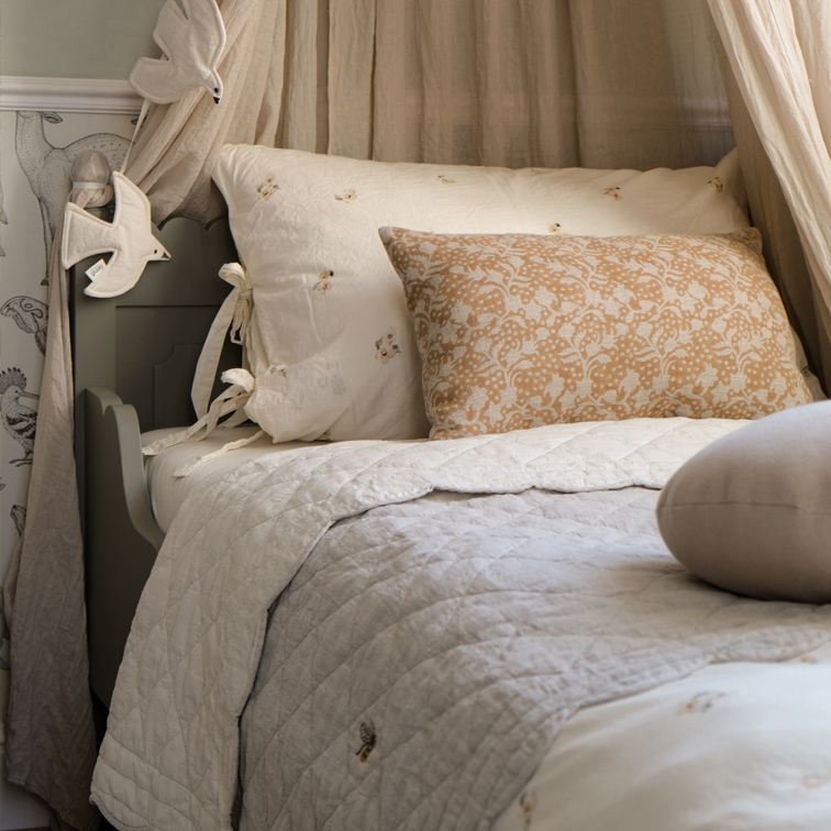 Letto accogliente con cuscino beige a motivo floreale e trapunta chiara trapuntata in cotone