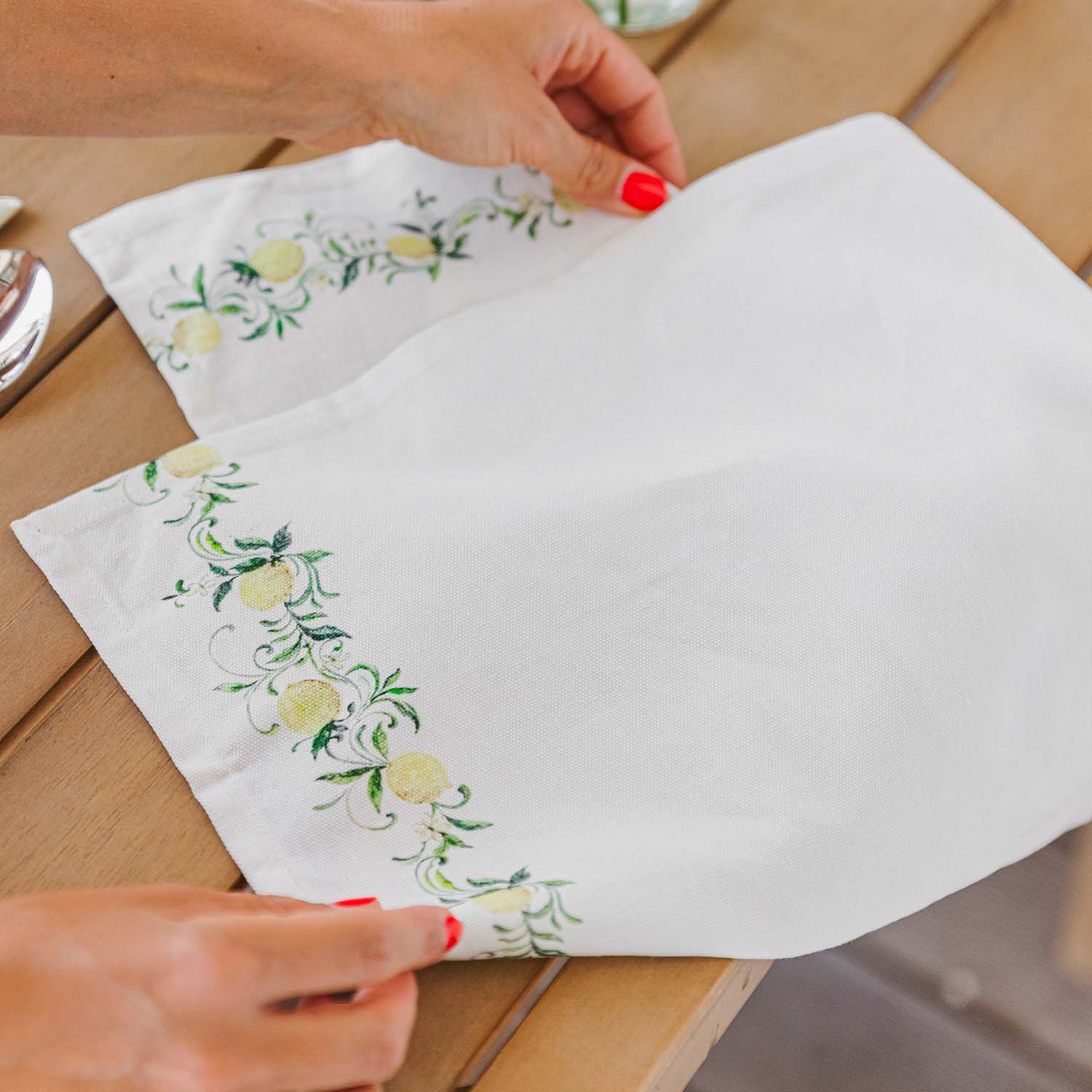 Tovagliolo di lino bianco con motivo limoni verde-giallo su tavolo in legno, decorazione tavola