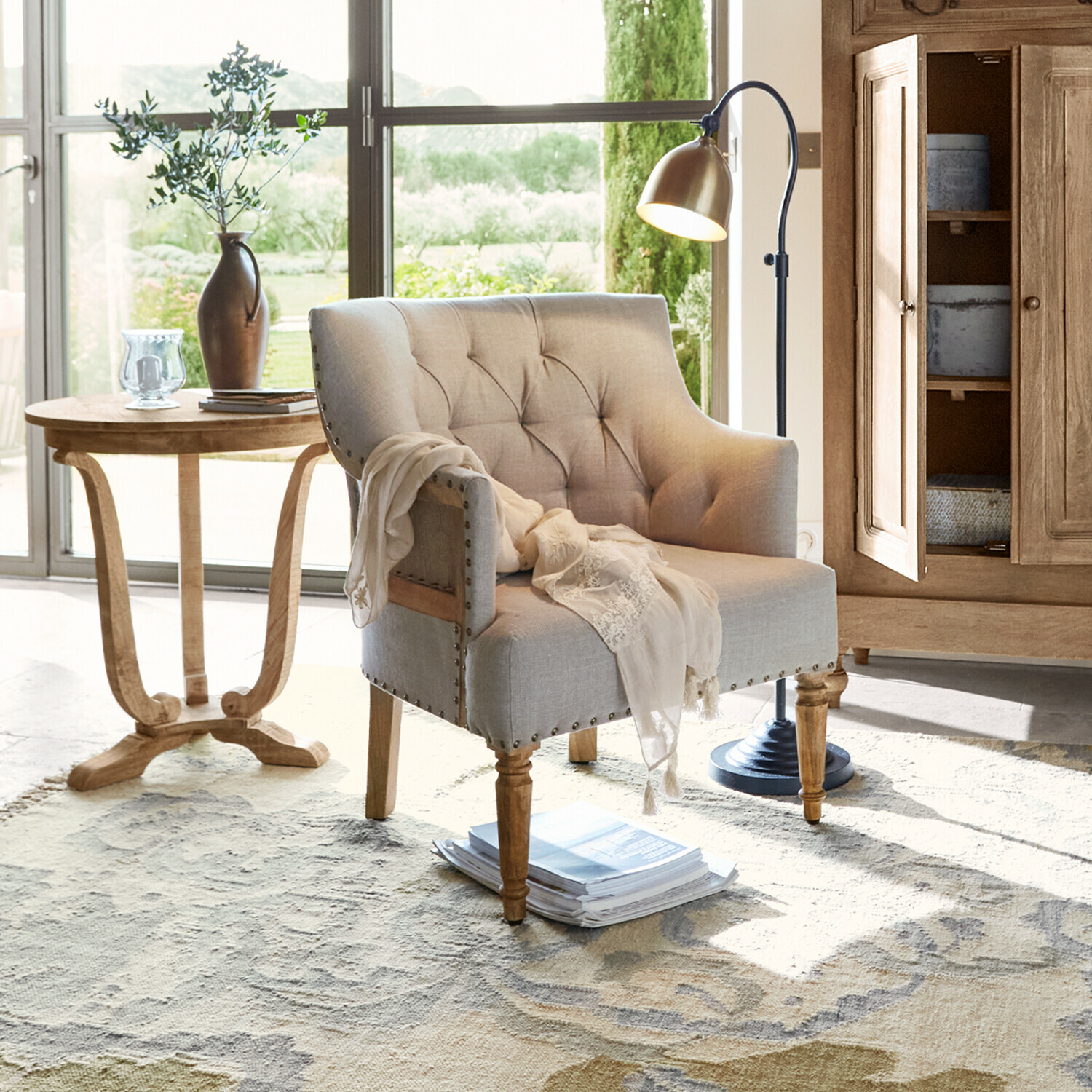 Poltrona Bebington Poltrona beige imbottita con gambe in legno in soggiorno luminoso con lampada e tavolino