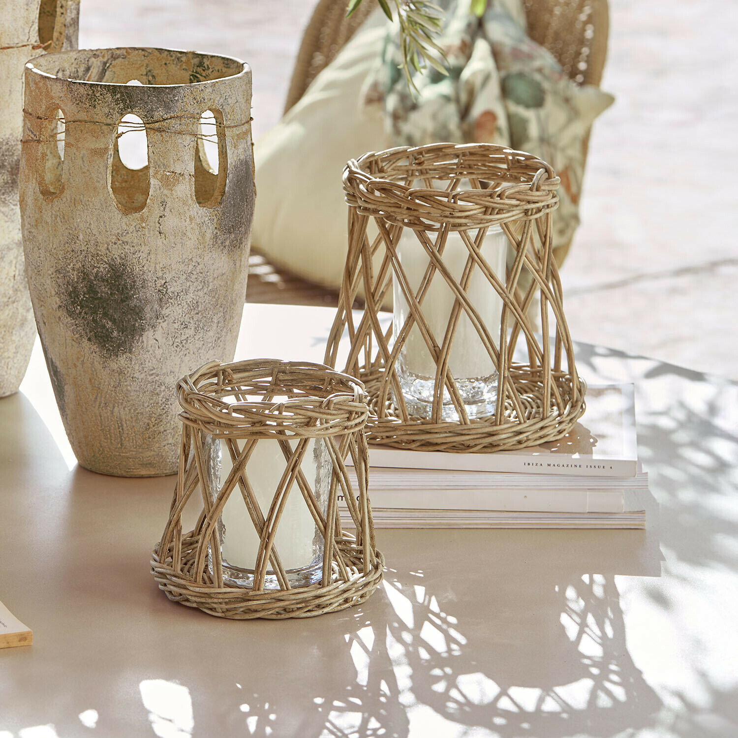 Coppia di lanterne Melari Due lanterne in rattan naturale con candele bianche su tavolo chiaro in stile boho
