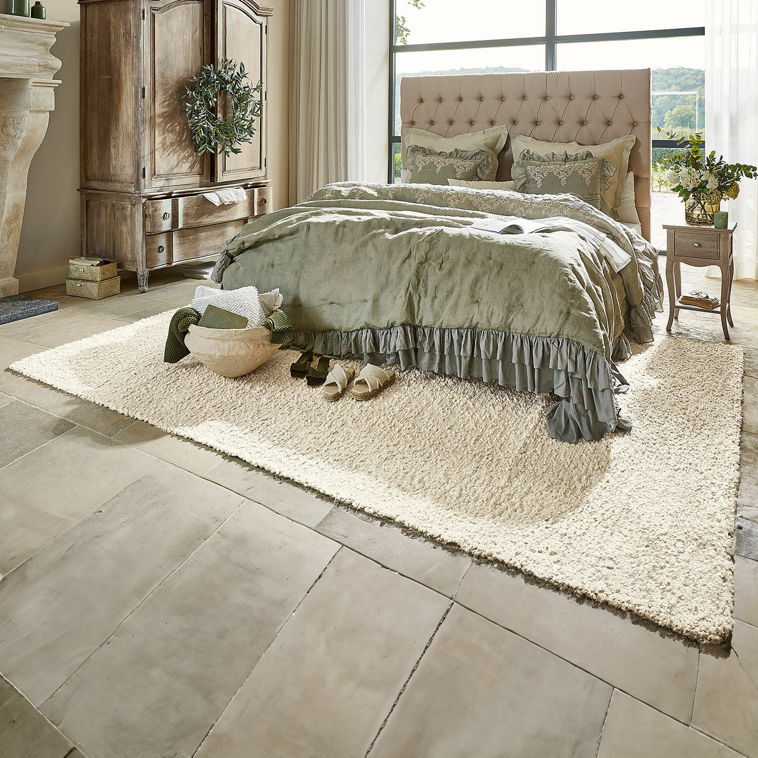 Tappeto Wodaha Camera accogliente con letto imbottito beige e biancheria da letto verde su tappeto crema su pavimento in pietra