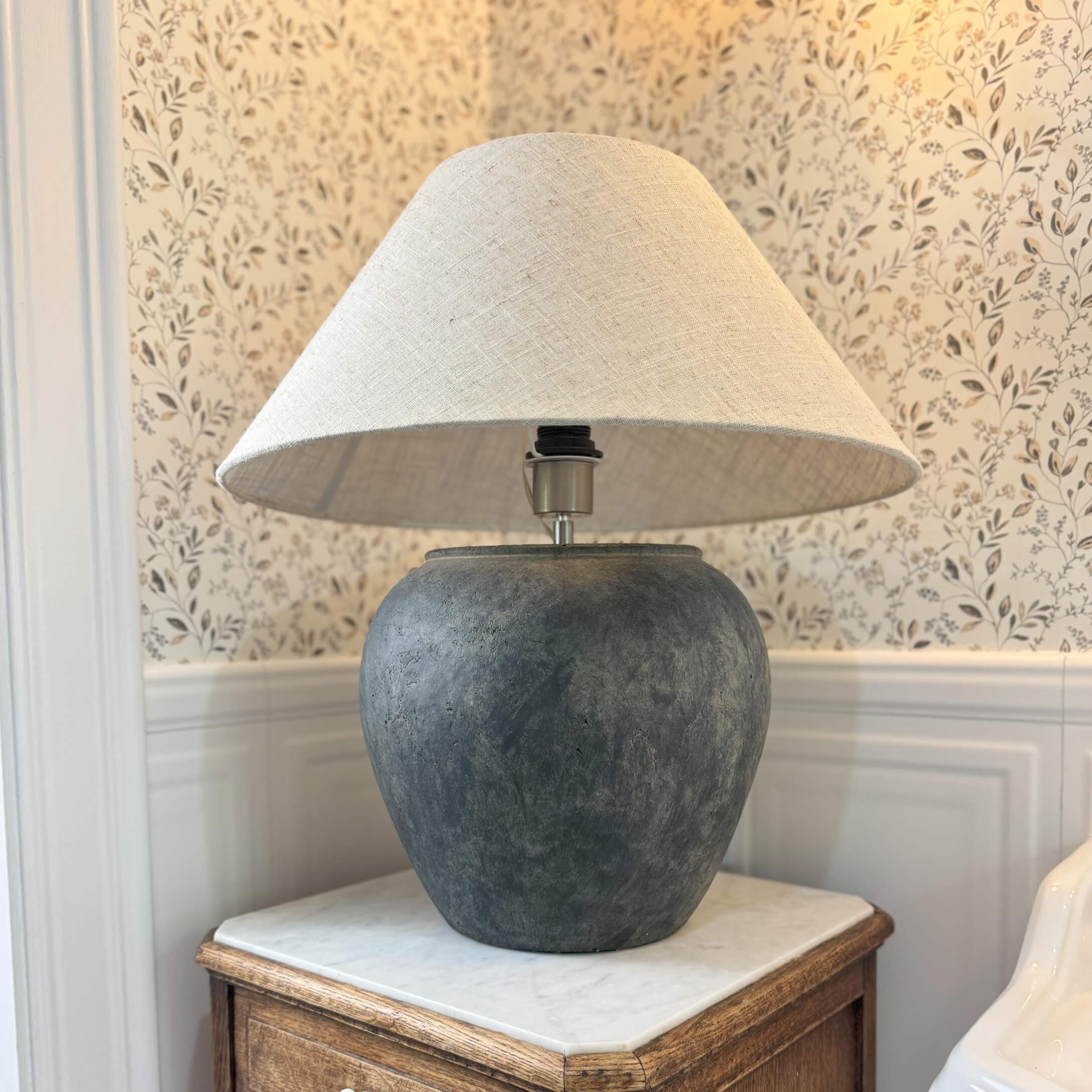 Lampada da tavolo in ceramica grigio scuro con paralume beige su tavolo in legno in ambiente classico