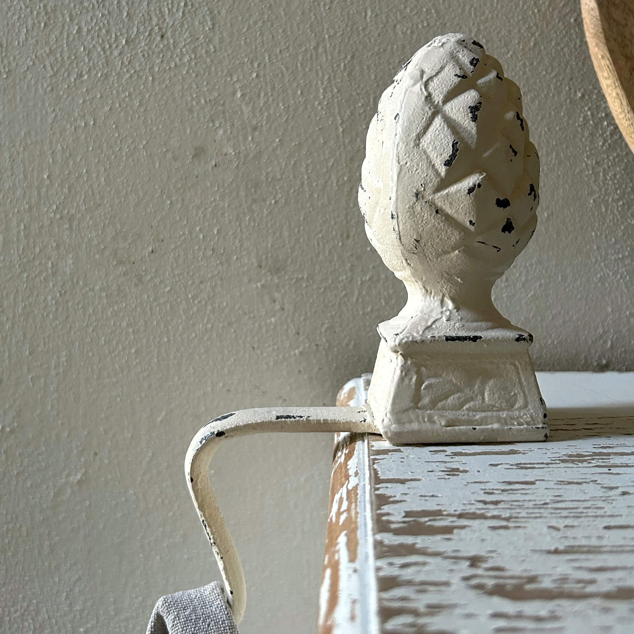 Maniglia in metallo bianco con ornamento a pigna su mobile in legno invecchiato