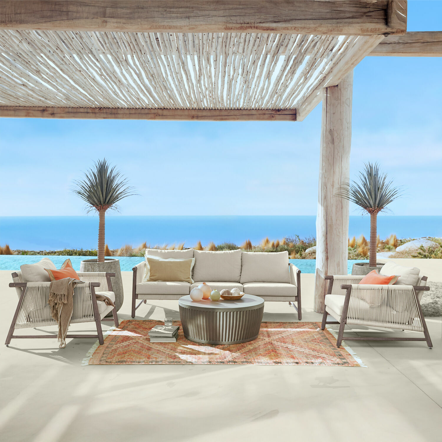 Salottino FSC®-100% Clarmontaine Set di mobili da esterno con cuscini beige e struttura in legno su terrazza con vista mare